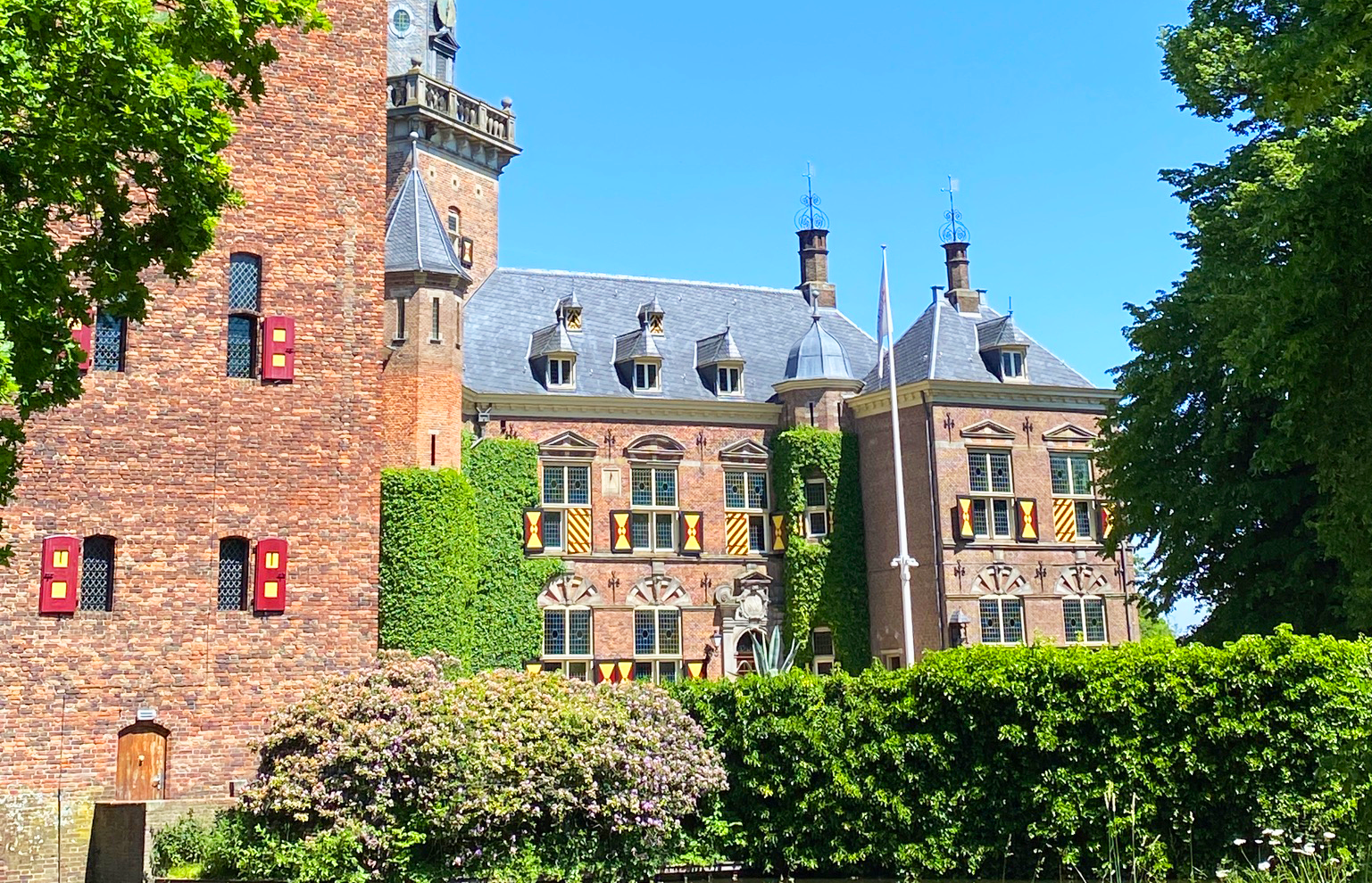 Kasteel Nyenrode omringd door bomen onder een blauwe lucht